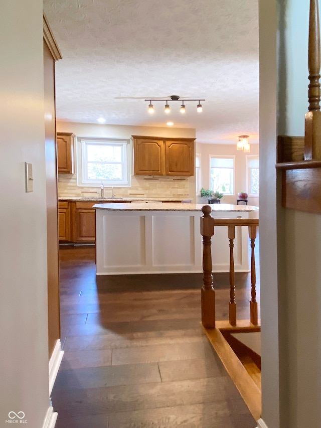 kitchen with plenty of natural light, dark hardwood / wood-style flooring, a textured ceiling, and backsplash