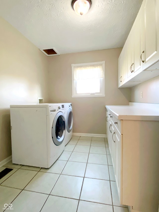 washroom with cabinets, light tile patterned floors, a textured ceiling, and independent washer and dryer