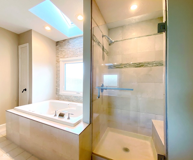 bathroom featuring shower with separate bathtub, a skylight, and tile patterned flooring