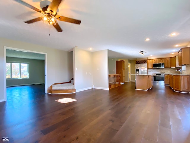 kitchen featuring tasteful backsplash, appliances with stainless steel finishes, a center island, and dark hardwood / wood-style flooring