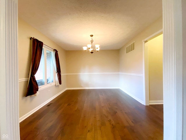 unfurnished room with a chandelier, a textured ceiling, and dark hardwood / wood-style flooring