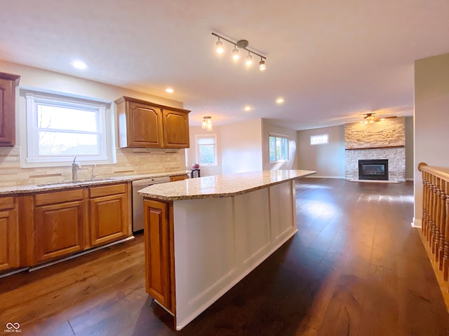 kitchen with sink, dishwasher, dark hardwood / wood-style floors, a center island, and decorative backsplash