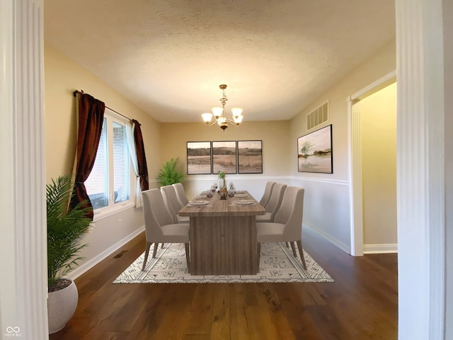 dining space with dark hardwood / wood-style flooring, a textured ceiling, and an inviting chandelier