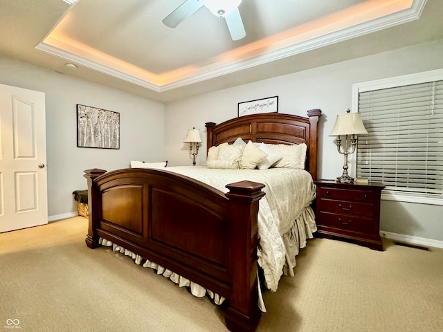 carpeted bedroom with a raised ceiling, ceiling fan, and ornamental molding