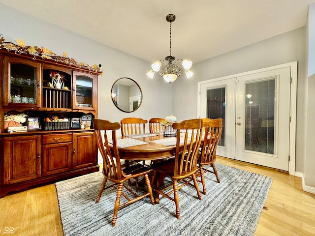 dining room with french doors, an inviting chandelier, and light hardwood / wood-style flooring