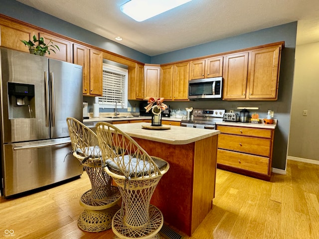 kitchen featuring a kitchen island, sink, appliances with stainless steel finishes, and light hardwood / wood-style flooring