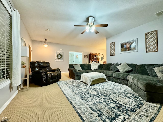 carpeted living room featuring ceiling fan and a textured ceiling