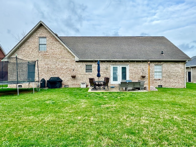 back of house featuring a yard, a trampoline, and a patio area