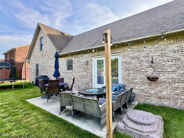 6998 Meredith Dr, Seymour, IN 47274 - back of property with roof with shingles, a trampoline, a patio, a lawn, and brick siding