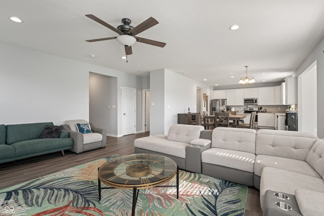 living room featuring ceiling fan with notable chandelier and dark hardwood / wood-style floors