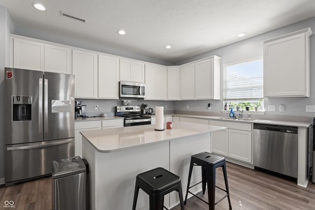 10797 Walden Ln, Brownsburg, IN 46112 - kitchen with appliances with stainless steel finishes, a sink, a kitchen bar, white cabinets, and recessed lighting
