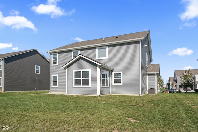 rear view of property featuring a yard and central air condition unit