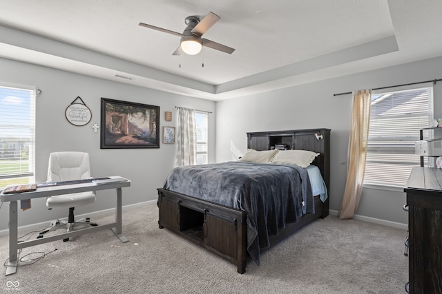 carpeted bedroom with a tray ceiling and ceiling fan