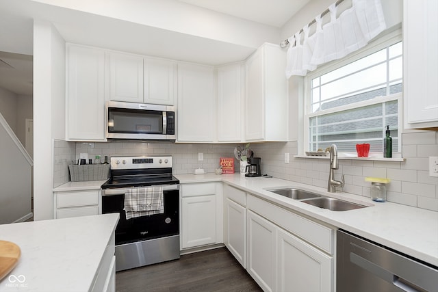 kitchen featuring decorative backsplash, appliances with stainless steel finishes, dark hardwood / wood-style flooring, sink, and white cabinetry