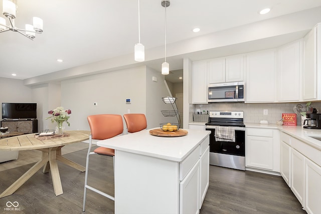 kitchen featuring dark wood-type flooring, hanging light fixtures, appliances with stainless steel finishes, a kitchen island, and white cabinetry