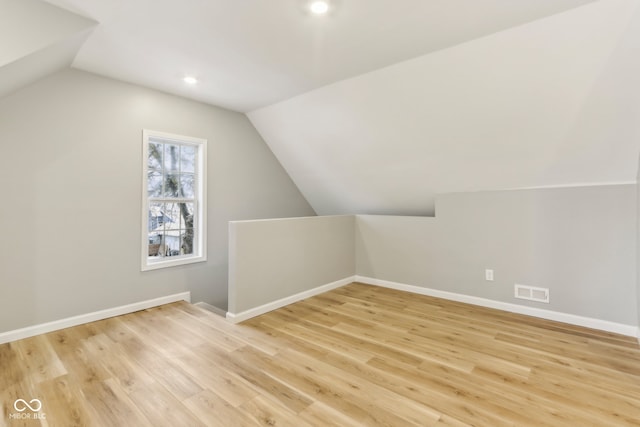 bonus room featuring light wood-type flooring and vaulted ceiling