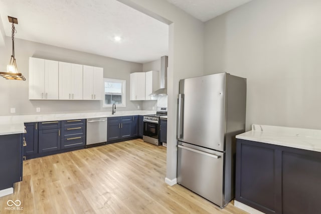 kitchen with pendant lighting, blue cabinets, light hardwood / wood-style flooring, appliances with stainless steel finishes, and white cabinetry