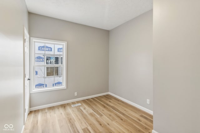 unfurnished room with a textured ceiling and light wood-type flooring