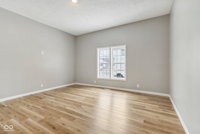 unfurnished room with light hardwood / wood-style floors and a textured ceiling