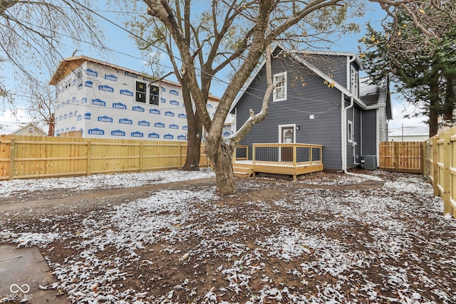 snow covered house featuring central air condition unit and a wooden deck