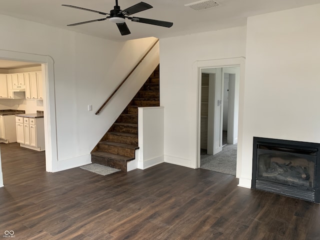 unfurnished living room featuring ceiling fan and dark wood-type flooring