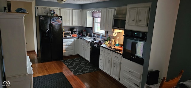 kitchen with a textured ceiling, sink, black appliances, dark hardwood / wood-style floors, and white cabinetry