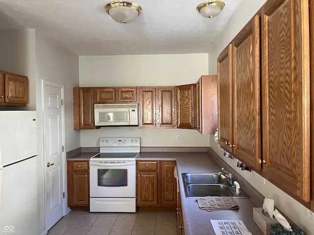 kitchen featuring a textured ceiling, sink, light tile patterned flooring, and white appliances