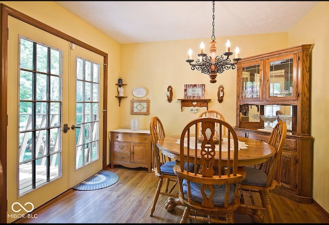 dining area featuring hardwood / wood-style flooring, vaulted ceiling, french doors, and an inviting chandelier