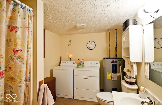 bathroom with electric water heater, washer and clothes dryer, a textured ceiling, and toilet