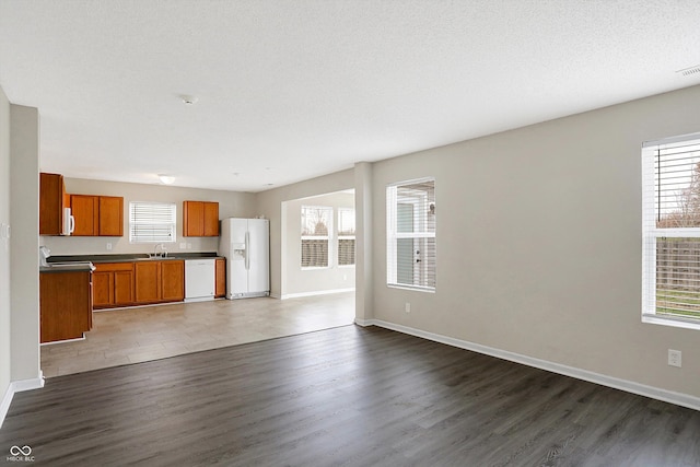 unfurnished living room with a healthy amount of sunlight, sink, and dark wood-type flooring