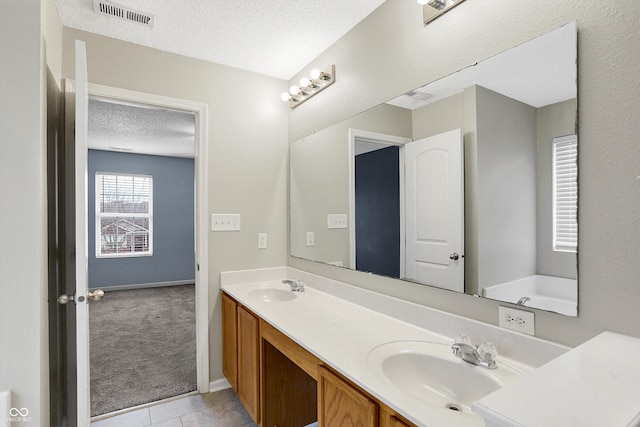 bathroom with tile patterned floors, vanity, and a textured ceiling