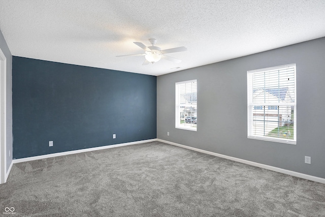 carpeted empty room featuring ceiling fan, a textured ceiling, and a wealth of natural light