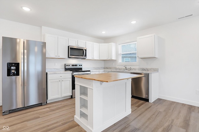 kitchen with wood counters, sink, appliances with stainless steel finishes, a kitchen island, and white cabinetry