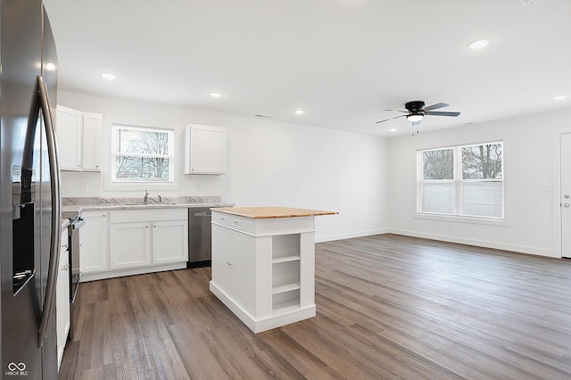 kitchen featuring white cabinets, a kitchen island, appliances with stainless steel finishes, and wooden counters