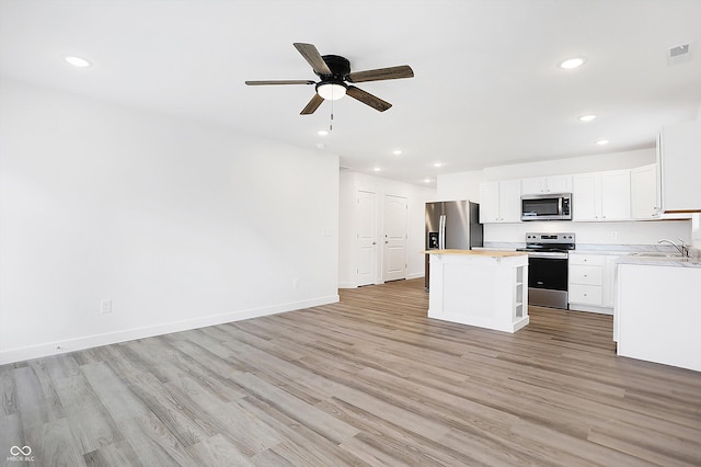 kitchen with a center island, wood counters, light hardwood / wood-style flooring, white cabinets, and appliances with stainless steel finishes