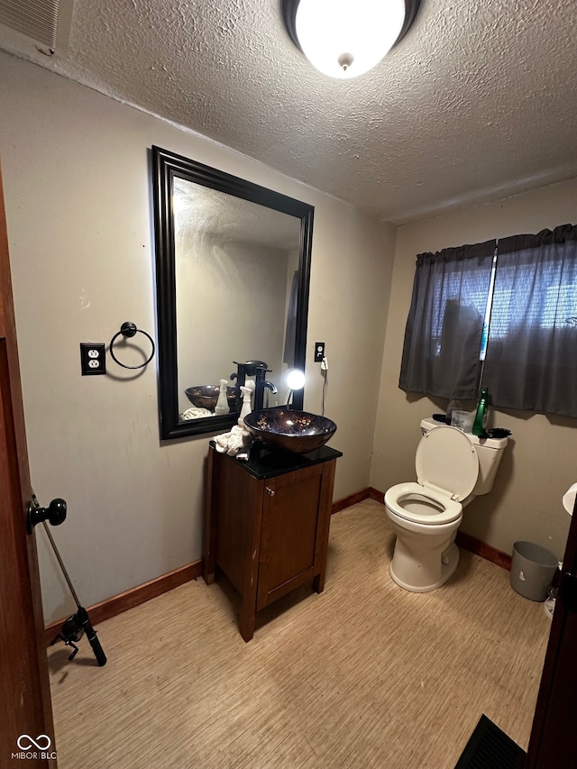 bathroom with a textured ceiling, vanity, hardwood / wood-style flooring, and toilet