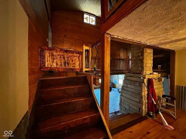 stairs with wood walls, lofted ceiling, and hardwood / wood-style flooring