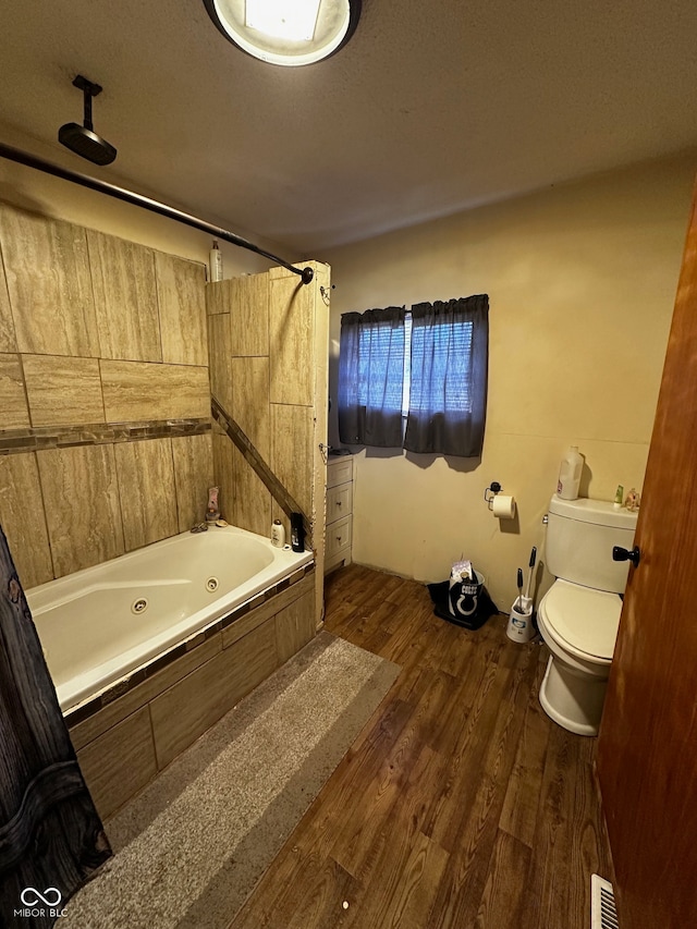 bathroom featuring toilet, wood-type flooring, a textured ceiling, and tub / shower combination