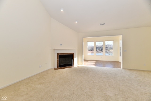 unfurnished living room with a tile fireplace, light carpet, and high vaulted ceiling