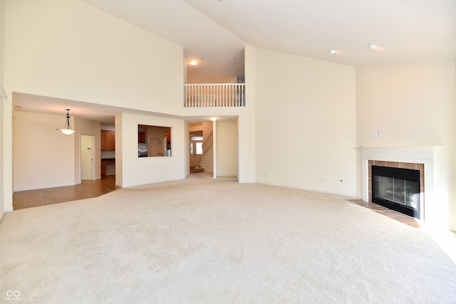 unfurnished living room with light carpet, a tile fireplace, and a high ceiling