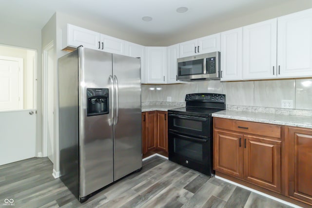 kitchen featuring light stone countertops, appliances with stainless steel finishes, tasteful backsplash, white cabinets, and dark hardwood / wood-style floors