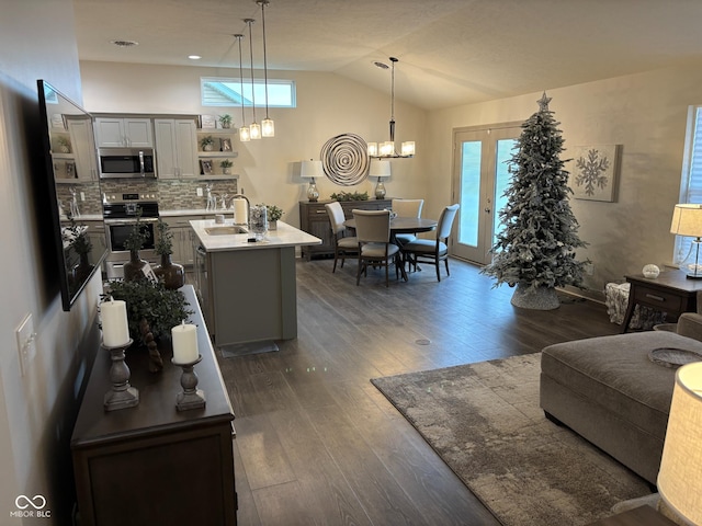 living room with sink, dark wood-type flooring, vaulted ceiling, and an inviting chandelier