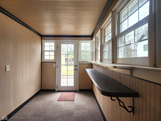 doorway to outside with carpet floors, crown molding, and wood ceiling