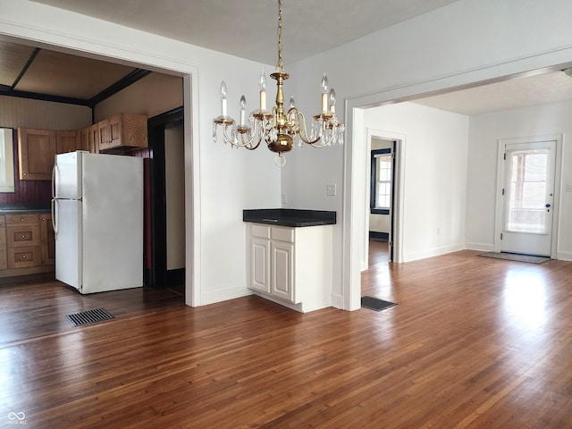 kitchen with hanging light fixtures, dark hardwood / wood-style floors, white refrigerator, crown molding, and a chandelier