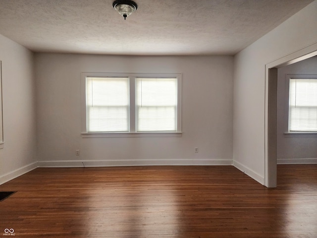 unfurnished room featuring a textured ceiling and dark hardwood / wood-style flooring