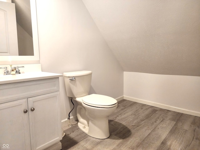 bathroom featuring hardwood / wood-style flooring, vanity, toilet, and lofted ceiling