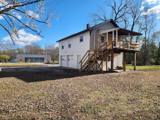 rear view of house featuring a deck and a garage