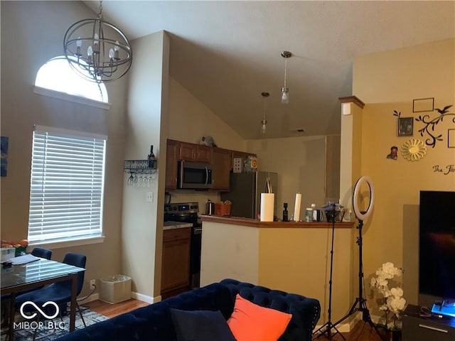 4112 Eagle Cove E Drive, Indianapolis, IN 46254 - kitchen with stainless steel appliances, light wood finished floors, a chandelier, high vaulted ceiling, and hanging light fixtures