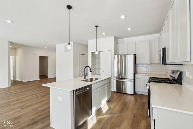 kitchen featuring backsplash, pendant lighting, a center island with sink, sink, and stainless steel appliances