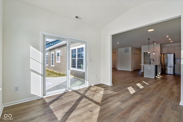 unfurnished living room with dark wood-type flooring, sink, and vaulted ceiling